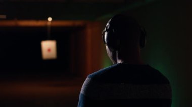 Atış talimi yapan gülümseyen bir adamın portresi, düzgün silah tutmayı ve eğlenmeyi öğrenmek. Neşeli silah meraklısı, silahlı, koruyucu gözlüklü, B kameralı.