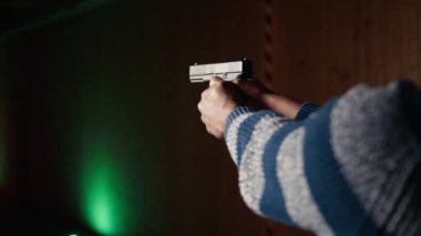 Atış poligonu müşterisi tabancayla ateş ediyor. Hedefe ateş edip etmediğini kontrol ediyor. Atış poligonunda silah kullanmayı öğrenen, hedeflerin görüntülerini analiz eden, kamera A.