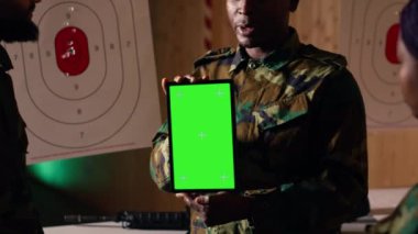 Askeri birlikler yeşil ekran tabletinde gerekli dövüş becerilerini öğrenmek için video izliyorlar. Ordu askerleri eğitim sırasında krom anahtar aygıt üzerindeki talimatlara bakıyor, kamera B