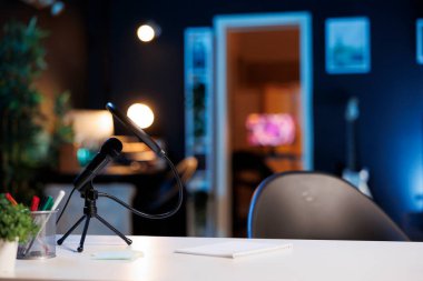 Mikrofonlu kahve masası ve loş ışıklandırmalı mini ev bitkileri. Aydınlatılmış apartman dairesinde podcast kayıt ekipmanları, yakın çekim