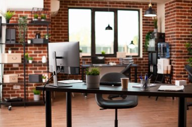 Bu boş, iyi düzenlenmiş çalışma alanı modern masa, masaüstü monitörü ve finansal belgelere sahip. Boş tuğla duvar odası iş projeleri ve pazarlama stratejisi geliştirme için hazır..