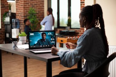 Bayan mali danışman ofis masasında oturuyor ve erkek müşteriyle görüntülü görüşme yapıyor. İş kadını bilgisayarını uzak meslektaşıyla sanal görüşme için kullanıyor, pazarlama stratejisi planlarını paylaşıyor.