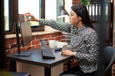 Asyalı bayan yönetici bunu şirket sunumuna hazırlanmak için masaüstü monitörüne yapıştırıyor. Resepsiyondaki genç iş kadını, proje hatırlatmaları için yapışkan notlar kullanıyor.