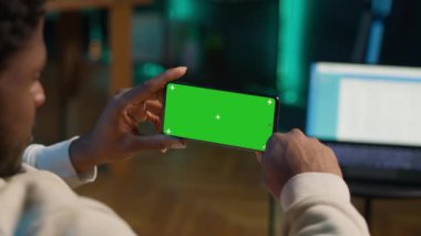 Afrikalı Amerikalı, modern moda evinin rahatlığı için yeşil ekranlı bir cihaz kullanıyor, kanepede oturuyor ve oturma odasında çalışıyor. Kendinden emin mutlu genç adam. Kamera A.