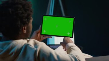 Afrikalı Amerikalı serbest yazar evindeki konfordan faydalanmak için tablet üzerinde fotokopi çekiyor, modaya uygun oturma odasındaki kanepede oturuyor. İnternette genç ve mutlu bir yetişkin. Kamera A.