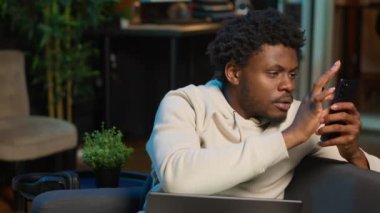 Black Freelancer araştırmasını evde makaleler ve veri odaklı kağıtlar okuyarak, telefon ve bilgisayar kullanarak yeni bir proje için bilgi toplayarak yapıyor. Adam birden fazla iş yapıyor ve dosyaları inceliyor. Kamera A.