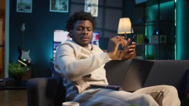 Black Freelancer araştırmasını evde makaleler ve veri odaklı kağıtlar okuyarak, telefon ve bilgisayar kullanarak yeni bir proje için bilgi toplayarak yapıyor. Adam birden fazla iş yapıyor ve dosyaları inceliyor. Kamera B.