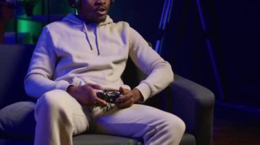 Konforlu evinde, video oyunları turnuvasında oynayan, rahatlayan ve eğlenen Afrikalı Amerikalı. Evde boş zamanlarında oyun konsolunda çok oyunculu bir oyuncu. Kamera A.