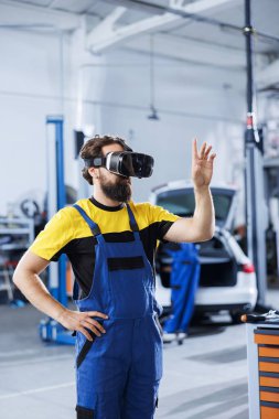 Araba servisindeki teknisyen, otomobil parçalarını tamir etmek için sanal gerçekliği kullanır. Araç sorunlarını çözerken fütüristik vr kulaklık takan bir garaj uzmanı