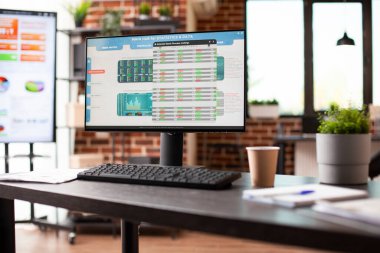 Masaüstü bilgisayarı ve iş analizi verilerini gösteren büyük dijital ekran masası olan boş çalışma alanı. Kimsesiz ofis masası, tuğla duvar odasında şirket istatistiklerini gösteren bilgisayar ekranı var..