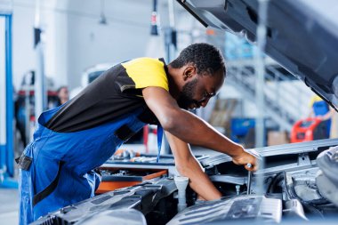 Mühendis, otomotiv performansını ve güvenliğini sağlamak için gelişmiş mekanik araçlar kullanarak araba dağıtımcısını ustalıkla inceliyor. Nitelikli garaj çalışanı yıllık araç kontrolü yapıyor