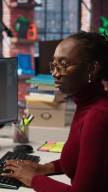 Dikey video, Silikon Vadisi risk programcısı AI LLM sohbet robotuyla öngörü teknolojisi kullanarak görevleri çözüyor. Üretici model kamera A ile etkileşim kurmak için bilgisayar kullanan Afro-Amerikan IT çalışanı