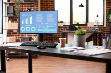 Bilgisayar monitörlü düzenli çalışma alanı veri analizi, defter ve belgeleri masasında gösteriyor. İnsansız, planlamaya ve projeyi tamamlamaya hazır bir duvar ofisi..