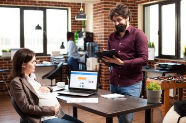 Hamile bir kadının beyaz erkek meslektaşı olarak karnını okşaması mali strateji planı sunuyor. Sakallı adam hamile iş arkadaşıyla beyin fırtınası yapıyor..