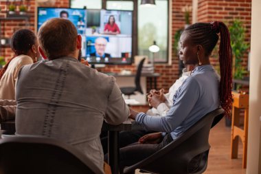 Sanal görüşmede çalışanların beyin fırtınası stratejileri dijital monitörde uzaktan kumanda ekibiyle işbirliği yapıyor. Ofis çalışanları ve müşteriler video görüşmeleri ile uzaktan bağlantı kuruyor, iş projelerini gözden geçiriyorlar.