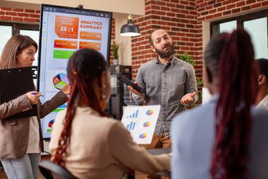 Beyaz erkek ve kadın meslektaşlar dijital ekranın önünde durmuş iş toplantılarındaki mali tabloları açıklıyorlar. Ofisteki proje tartışmaları sırasında çok ırklı iş arkadaşları görüşlerini paylaşıyor.