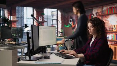 Uygulamalar oluşturmak için IT 'nin başlangıç ofisinde programlama dillerini kullanan gülümseyen kadın. A kamerasını kodlamak için yazılım geliştirme ajansındaki bilgisayarı kullanan iyimser programcı.