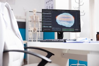 Doktor ofisinde beyin görüntüleme verilerini gösteren bilgisayar ekranlı işlenmemiş bir masa. Hastanedeki gelişmiş teknolojinin insan kafası tarafından vurgulanmasının radyoloji sonuçlarını gösteren modern bilgisayar monitörü.