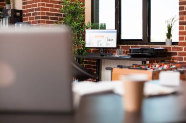 Bilgisayarında mali tabloları olan tuğla duvar odası, masasında güzel mobilyalar ve bitki süslemeleriyle çevrili yazıcı. İş verilerini gösteren dizüstü bilgisayarlar, bitkiler ve masaüstü bilgisayarı olan başlangıç ofisi.