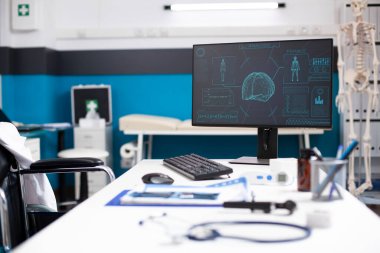 Beyin ve vücut taramalarını gösteren bilgisayar ekranı olan boş bir klinik odası. Nöroloji ve bilgisayarlı tomografi üzerine odaklanmış. Tıbbi dosyalar ve modern ekipmanlarla dolu doktor masası sağlık analizi için hazır..