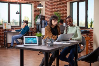 İş kadınları yan yana oturur, makaleleri analiz eder ve dizüstü bilgisayarla tartışırken fikirlerini paylaşırlardı. Şirket büyüme istatistiklerini gösteren tablet ofis masasında çalışan kadın iş arkadaşları.