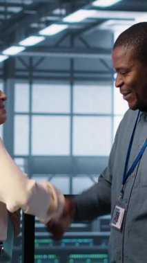 Raporları ve dosyaları gözden geçirmek ve tokalaşmak için veri merkezinde toplanan dikey video yöneticileri. Sunucu odası çalışanı iş arkadaşını selamlıyor, arayı kapatmak için sorun atışı yapıyor, kamera A