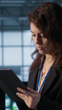 Veri merkezinde dikey video teknisyeni, tablet entegre yapay zeka otomasyon araçları, öngörü bakım rutinleri. Sunucu odasının sürekli güncellenmesini sağlayan, verileri yöneten kadın