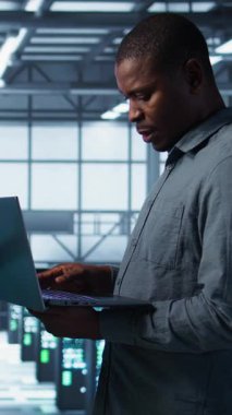 Güvenlik duvarı yapılandırmalarını doğrulayan cihazlar kullanarak veri merkezindeki mutlu sistem yöneticilerinin dikey video portresi. Jolly takım çalışması bilişim uzmanları sunucuda ekipman savunmasızlığı taraması yapıyor