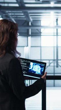 Dikey video veri merkezi teknisyenleri tablet kullanarak yapay zeka kullanan yönetim araçları kullanıyorlar. Sunucu çiftliği iş arkadaşları sunucu kümelerini denetliyor, ağ topolojilerini yapay zeka kullanarak güncelliyor