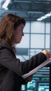 Dikey Veri Merkezi ekibi sunucu odasındaki evrak dosyalarını inceleyip sistem teşhislerini inceliyor. Sunucu odası çalışanları bakım çizelgelerini ve siber güvenlik protokollerini inceliyor. Kamera A