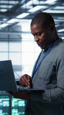 Veri merkezindeki dikey video meslektaşları enerji kullanımını ayarlamak için dizüstü bilgisayar kullanır. UPS ayarlarını denetlemek için dizüstü bilgisayar kullanan sunucu çiftliği bilişim uzmanı, ekipman ve kamera bakımı yapıyor