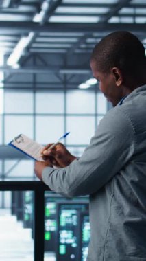 Raporları ve dosyaları gözden geçirmek ve tokalaşmak için veri merkezinde toplanan dikey video yöneticileri. Sunucu odası çalışanı iş arkadaşını selamlıyor, arayı kapatmak için sorun vuruşu yapıyor, kamera B