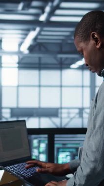 Veritabanı işletim defterinde dikey video mühendisi, yeni sunucu mimarileri kuruyor. Sunucu çiftlik çalışanı dizüstü bilgisayar kullanarak ayarları doğrulayan, sabit ağ performansını koruyan, kamera B