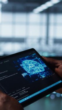 Veri merkezindeki dikey video programcısı tablette yapay zeka teknolojisi kullanarak ekipman arızalarını test ediyor. Sunucu çiftliği bilişim uzmanı aygıt üzerinde veri erişimini sağlamak için yapay zeka kullanıyor