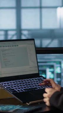 Veri merkezinde dizüstü bilgisayar kullanan dikey video teknisyeni, ağ protokollerini düzenleyen, kahve fincanı tutan. Sunucu odasındaki kadın not defterine kodlama yapıyor, gelişmiş güvenlik önlemleri uyguluyor, kamera A