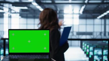 Veri merkezinde yürüyen yazılım geliştiricilerinin önündeki model dizüstü bilgisayar, ekipman teşhislerini gözden geçiriyor. Sunucu çiftliğindeki takım çalışması yapan bilişim uzmanlarının yanındaki izole ekran defterini kapat