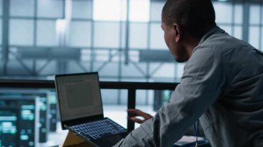 Veri merkezinde bilgisayar kullanan, güç yönetimi ayarlarını ayarlayan, programlama dilleri kullanan bir teknisyen. Sunucu odasındaki adam kaynak kullanımını optimize ediyor, istikrarlı altyapıyı koruyor, kamera A