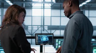 Veri merkezi ekibi sunucu odasındaki evrakları inceliyor, tabletteki yapay zekayı kullanarak sistem raporlarını analiz ediyor. Yapay Zeka sunucu odası yöneticileri finansal belgeleri inceliyor, kamera A