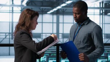 Veri merkezi ekibi sunucu odasındaki evrak dosyalarını inceliyor, sistem tanılarını inceliyor. Sunucu odası çalışanları bakım çizelgelerini ve siber güvenlik protokollerini inceliyor. Kamera A