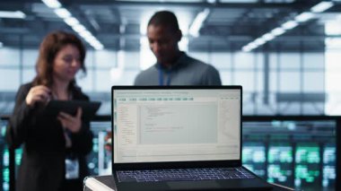 Bilgisayar ekranındaki kod satırları takım çalışması veri merkezi meslektaşları tarafından güvenlik yamalarını çalıştırmak için kullanılır. Bilgi işlem uzmanları tarafından kullanılan dizüstü bilgisayardaki programlama dili tarama donanımı, kamera B kapat