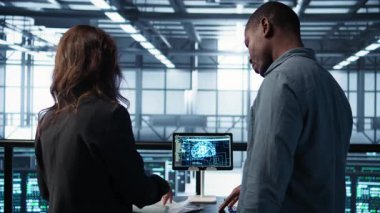 Veri merkezi ekibi sunucu odasındaki evrakları inceliyor, tabletteki yapay zekayı kullanarak sistem raporlarını analiz ediyor. Yapay zeka sunucu odası yöneticileri mali belgelere bakıyor, kamera B