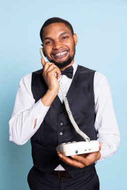 Profesyonel kapıcı telefon görüşmesinde oda rezervasyonu yapar ve otel konaklarına yardım etmek için gerekli olanakları ve tesisleri tartışır. Takım elbiseli ve kravatlı belboy uzaktan arıyor..