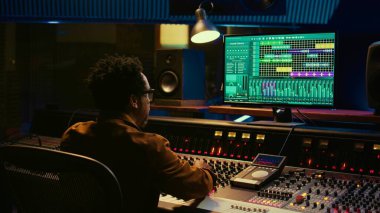 Ses uzmanı ses kabininde şarkı söyleyen sanatçı için geri sayım yapıyor. Yapımından sonra bunları düzenlemek için şarkılar kaydediyor. Yapımcı, karıştırma konsolunu, düğmeleri ya da sürgüleri, kontrol odasını çalıştırır. Kamera B.
