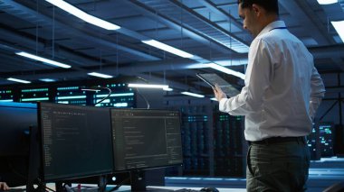 Veri merkezi mühendisi. Cihaz üzerindeki ağ donanımının kurulumu ve onarımından sorumlu. Bilgi işlem uzmanı sunucu odası altyapısında tablet, kamera B kullanarak bakım yapıyor.