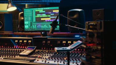 Ses parçalarını karıştırmak ve ustalaştırmak için kullanılan daw yazılımıyla müzik kayıt stüdyosu kontrol odası, ses geçirmez boş profesyonel alan. Ses dalgalarını düzenlemek için kontrol panelindeki modern kaydırıcılar.