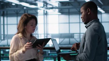 Sunucu odasında bilgisayar ve tablet kullanarak veri bilimcileri, güvenlik yamalarını çalıştırarak, güvenlik duvarı yapılandırmalarını doğrulayarak. Veri merkezinde, kamera A 'da ekipman hassasiyeti taraması yapan insanlar