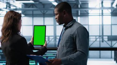 Veri merkezindeki bilgisayar bilimcileri taklit tablet kullanıyor, sunucu donanımlarını denetliyor, cihazları güncelliyor. Krom anahtar cihazı, kamera A kullanılarak dengeli işlemleri sağlamak için işbirliği yapan bilişim bilimci meslektaşları