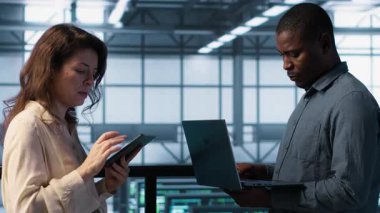 Veri merkezindeki mutlu sistem yöneticilerinin portresi, güvenlik duvarı yapılandırmalarını doğrulayan cihazlar kullanıyor. Jolly takım çalışması bilişim uzmanları sunucu merkezinde ekipman savunmasızlığı taraması yapıyor, kamera A