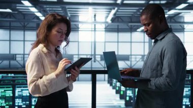 Veri merkezindeki mutlu sistem yöneticilerinin portresi, güvenlik duvarı yapılandırmalarını doğrulayan cihazlar kullanıyor. Jolly takım çalışması bilişim uzmanları sunucu merkezinde ekipman savunmasızlığı taraması yapıyor, kamera B