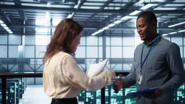 Veri merkezi mühendisi meslektaşımı selamlıyor, sistem teşhis belgelerini birlikte inceliyorlar. Sunucu odası çalışanları tokalaşıyor, bakım raporlarına bakmak için toplanıyorlar, kamera B